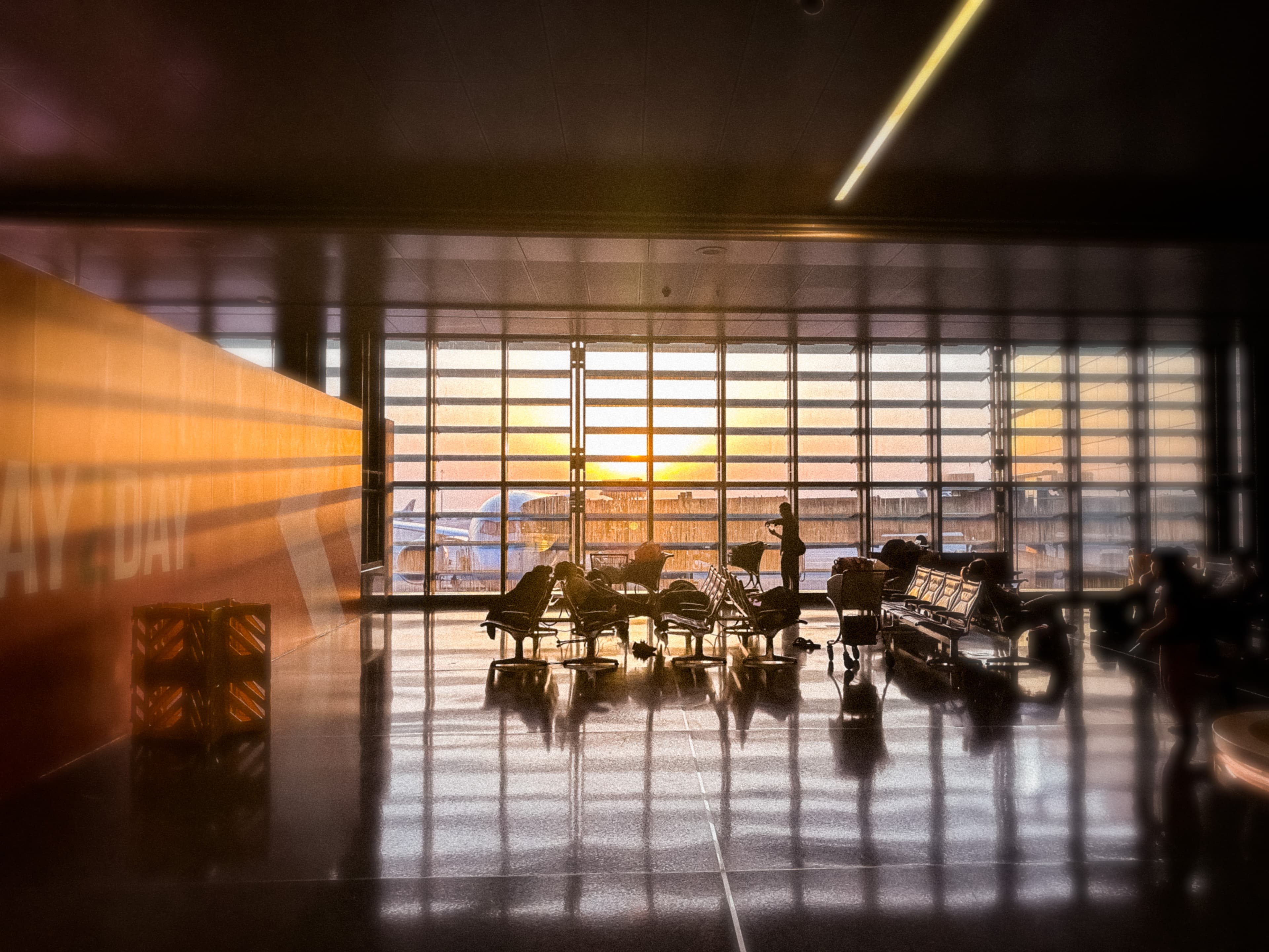 Travellers silhouetted by warm light inside an airport