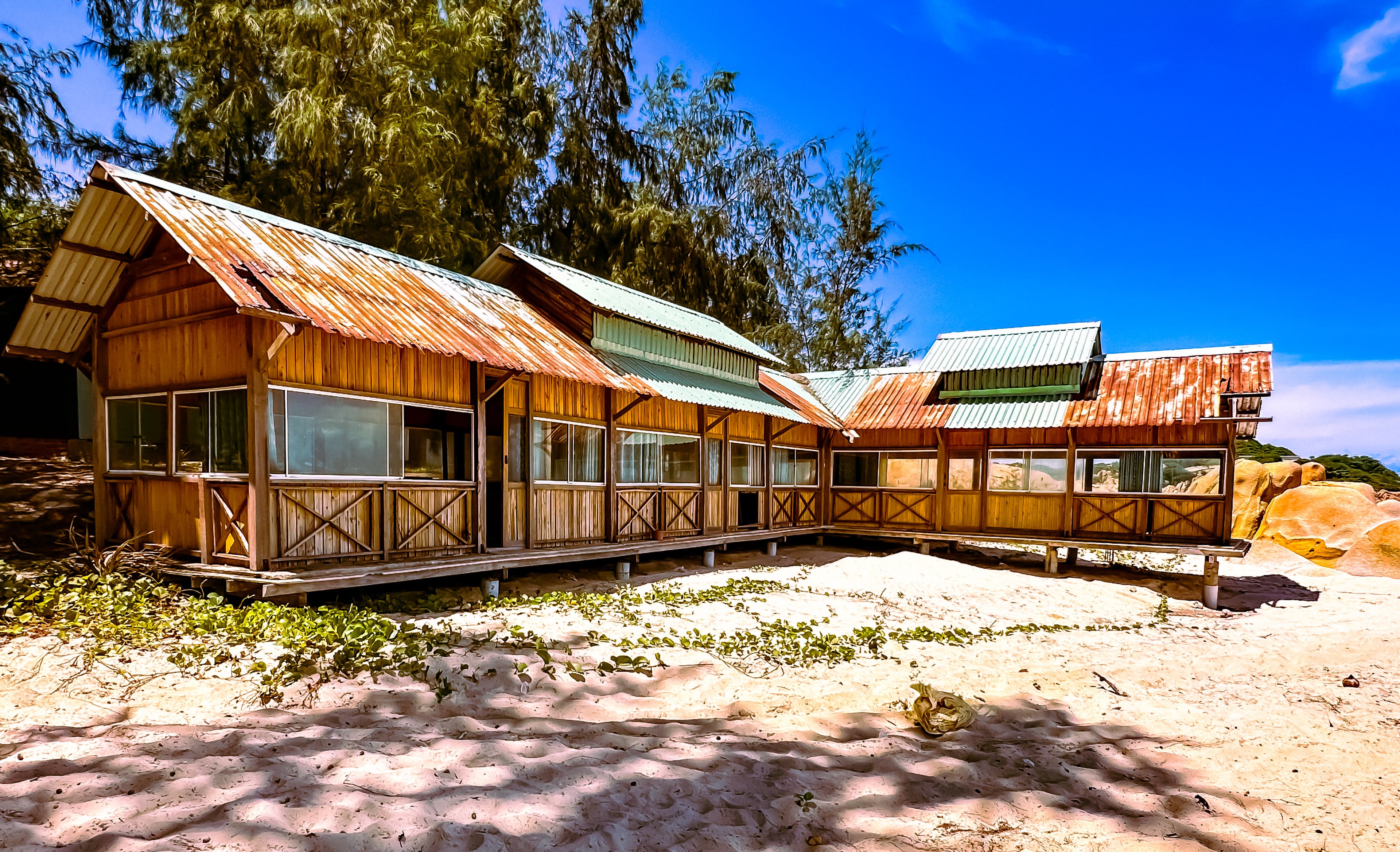 Sunlit abandoned wooden buildings beside a beach