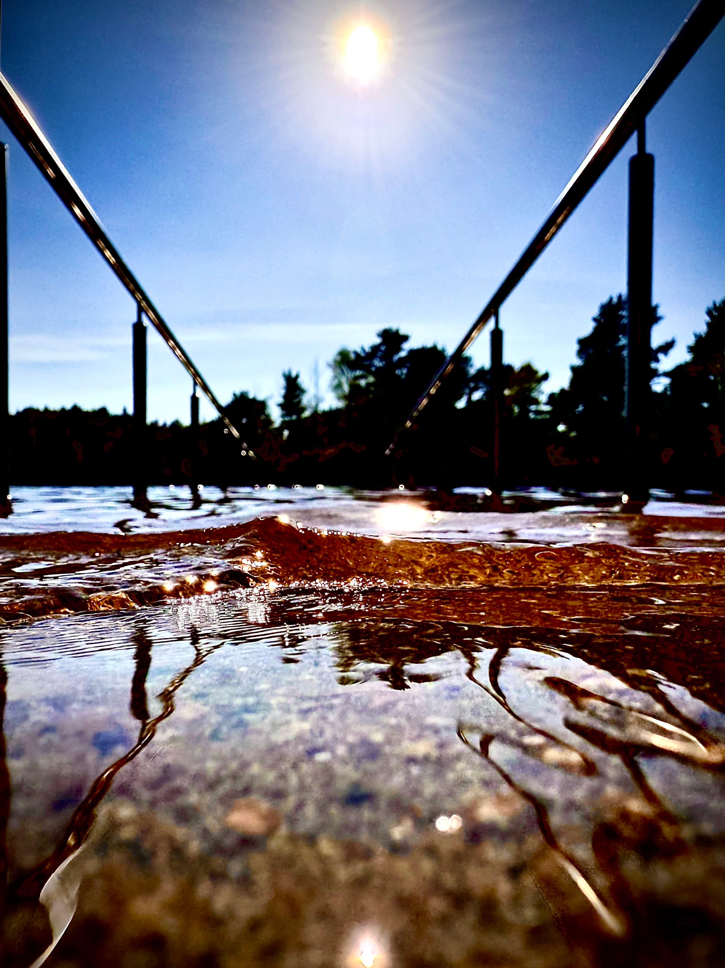 A low wave catching warm light beneath a bridge